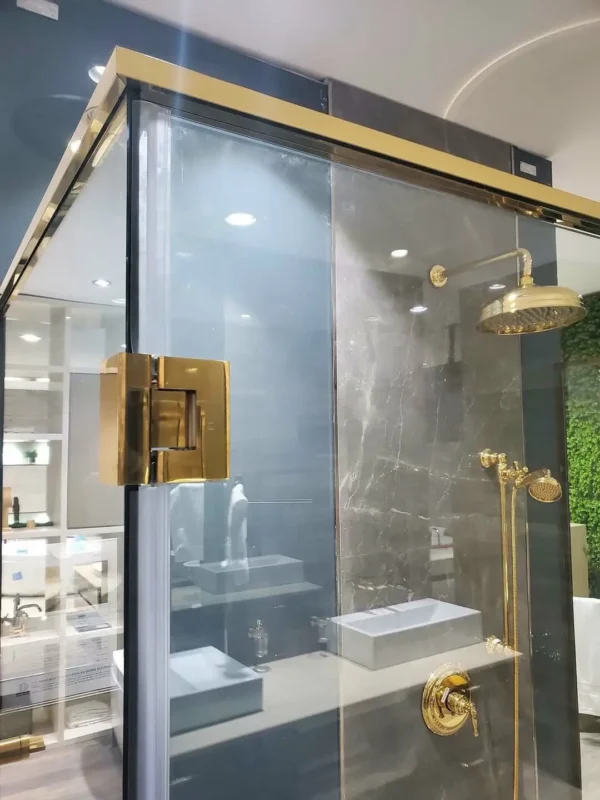 Cận cảnh bản lề màu vàng gắn cánh cửa kính của cabin tắm mở quay
