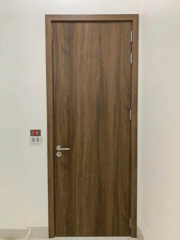 Cửa composite phẳng vân gỗ nâu đậm, tay gạt inox, ba bản lề, khung bao cùng màu