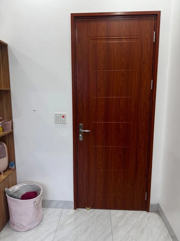 Cửa composite tại Thái Bình cho cửa phòng, cánh nâu đỏ khắc rãnh ngang, tay gạt inox
