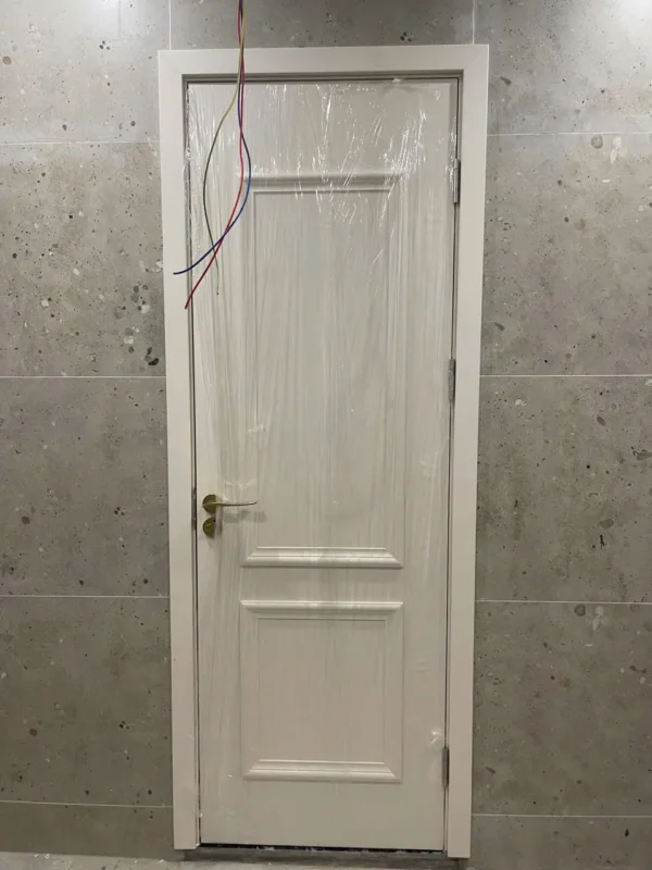 Cửa composite trắng hai ô nổi tay nắm vàng, nẹp khung bao ôm sát tường gạch xám