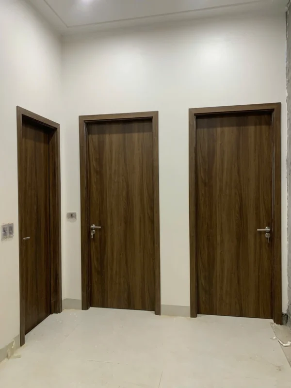 Ba cửa composite phẳng màu nâu đậm lắp cạnh nhau trong hành lang, tay gạt inox