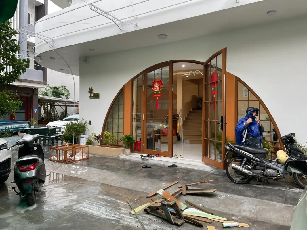 Cửa nhôm kính vòm cung màu vân gỗ chia ô nhỏ, cánh mở quay ở lối vào