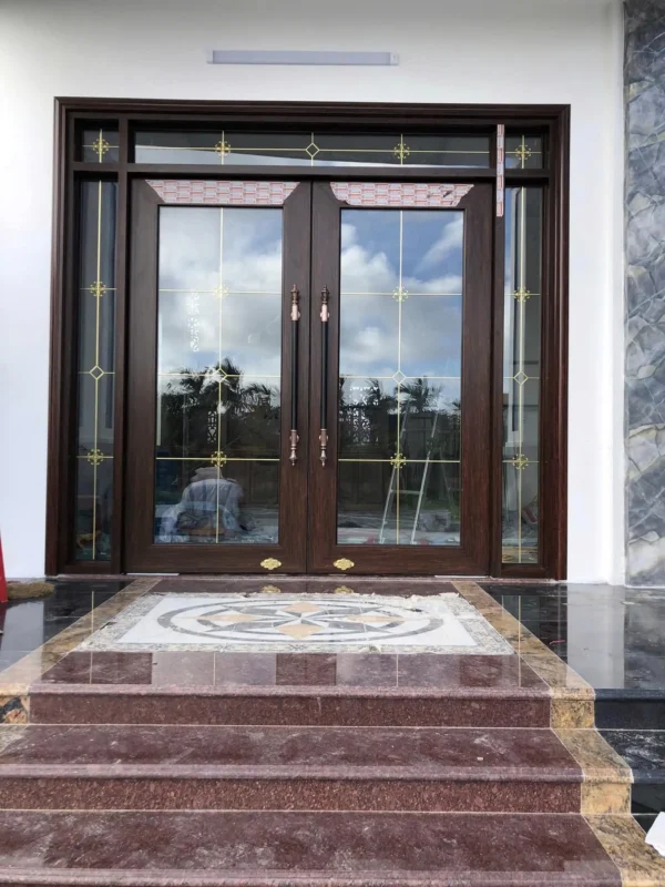 Cửa nhôm thủy lực Xingfa màu vân gỗ nâu đậm, lắp trước bậc thềm ốp đá đỏ