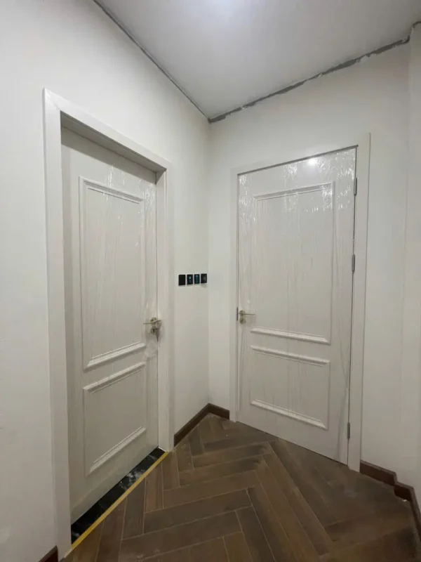 Hai cửa composite màu trắng hai ô nổi ở hành lang lát sàn gỗ xương cá