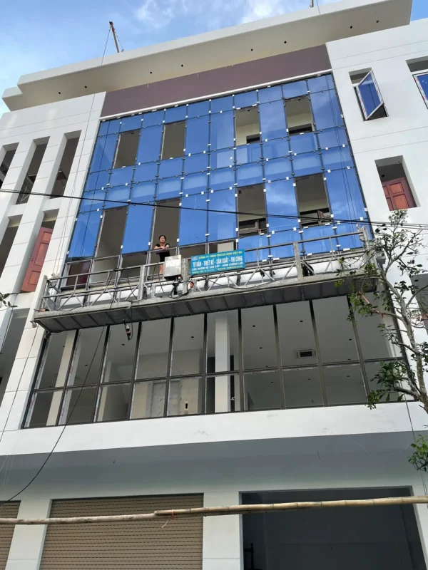 Gôn nâng hạ treo biển Kính Việt Hà trước mặt dựng kính xanh đang lắp ở mặt tiền nhà phố