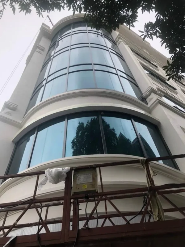 Mặt dựng kính uốn cong ôm góc nhà phố kiểu tân cổ điển, khung nhôm tối màu chia ô ngang