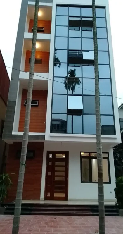 Nhà phố nhiều tầng có mặt dựng kính khung nhôm tối màu bên cạnh các ban công ốp màu gỗ