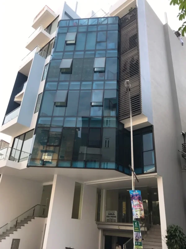 Mặt dựng kính xanh lục nhạt nhô ra ở góc tòa nhà văn phòng nhiều tầng, có các ô cửa mở hất
