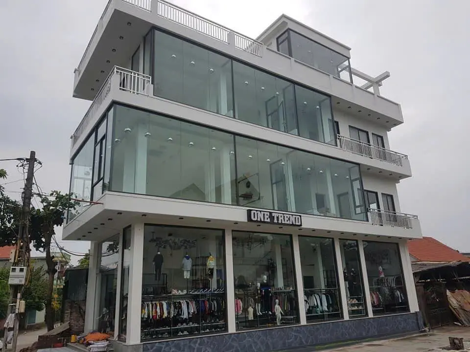 Mặt tiền cửa hàng thời trang bốn tầng có vách kính lớn và cửa nhôm kính ở tầng trệt
