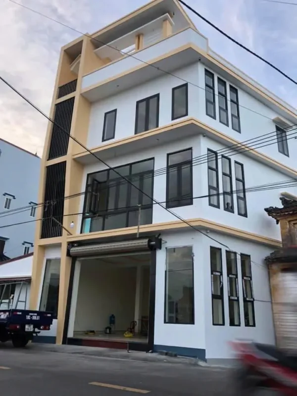 Nhà phố bốn tầng mặt đường lắp cửa sổ nhôm kính khung đen và cửa cuốn ở tầng trệt