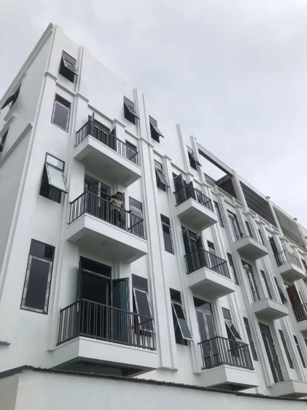 Nhà ở nhiều tầng sơn trắng lắp cửa sổ nhôm mở hất, cửa ban công và lan can sắt