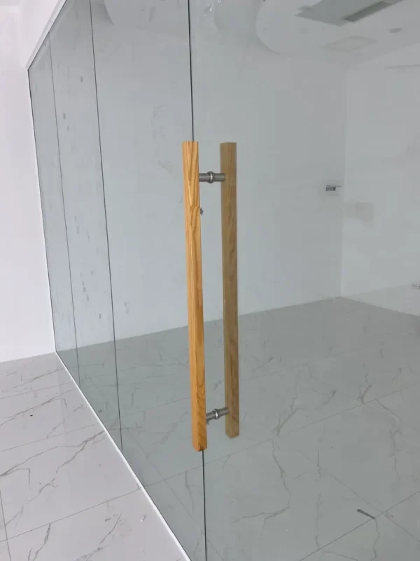 Cận cảnh tay nắm inox màu vân gỗ trên cửa vách kính cường lực