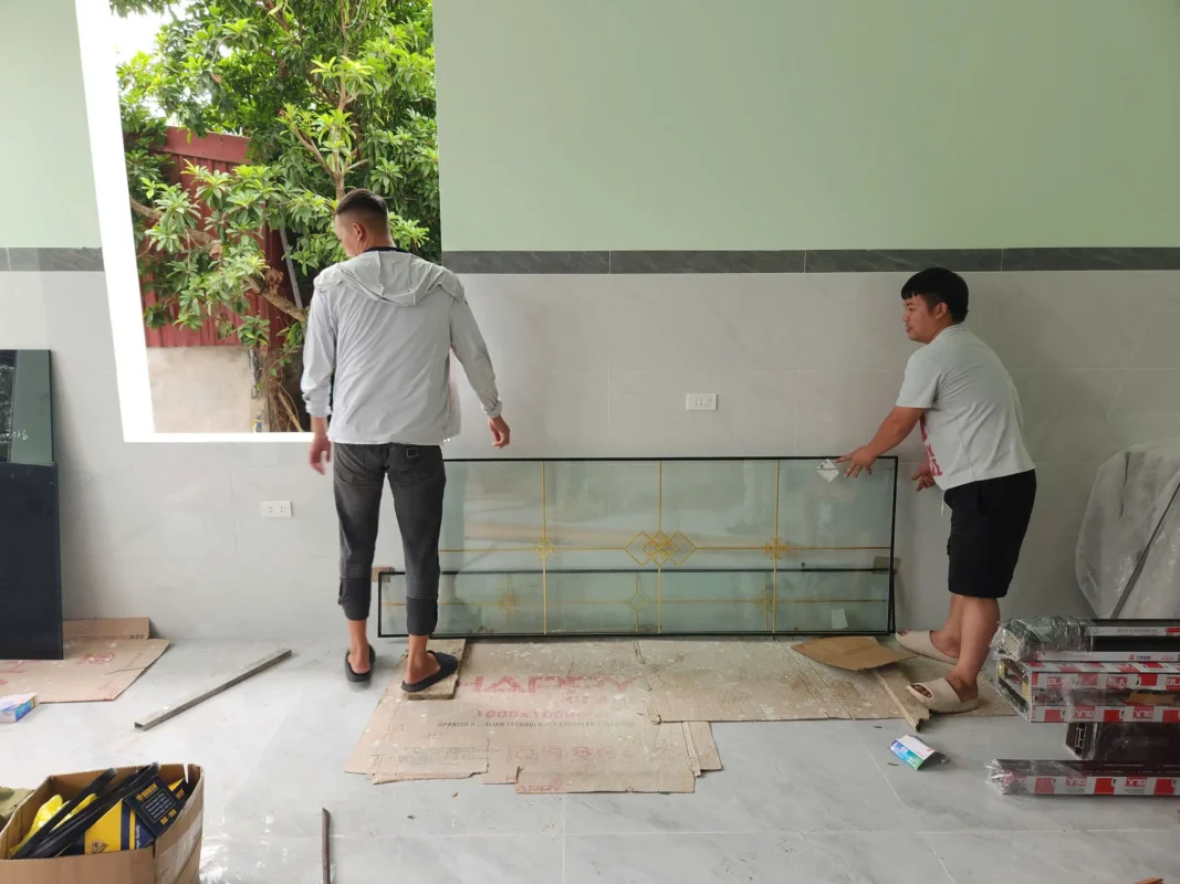 Đội thợ vận chuyển kính vào công trình để lắp cửa